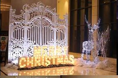 Illuminated white gate installation with 'Merry Christmas' marquee letters and light reindeer