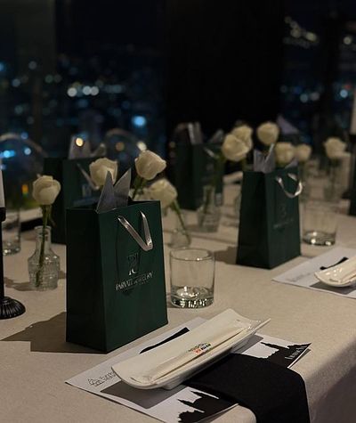 Delegate gifting table with branded bags and single white roses at each place setting