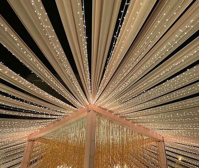 Garden lawn celebration with a draped white canopy and a chandelier over the dining table