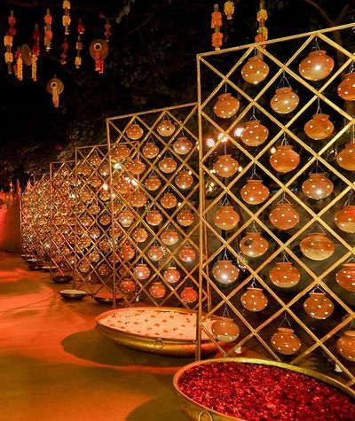 Gold jaali screens lit with warm globes above a rose petal water feature