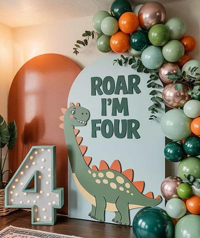 Dinosaur themed fourth birthday party with a balloon garland and illuminated marquee number