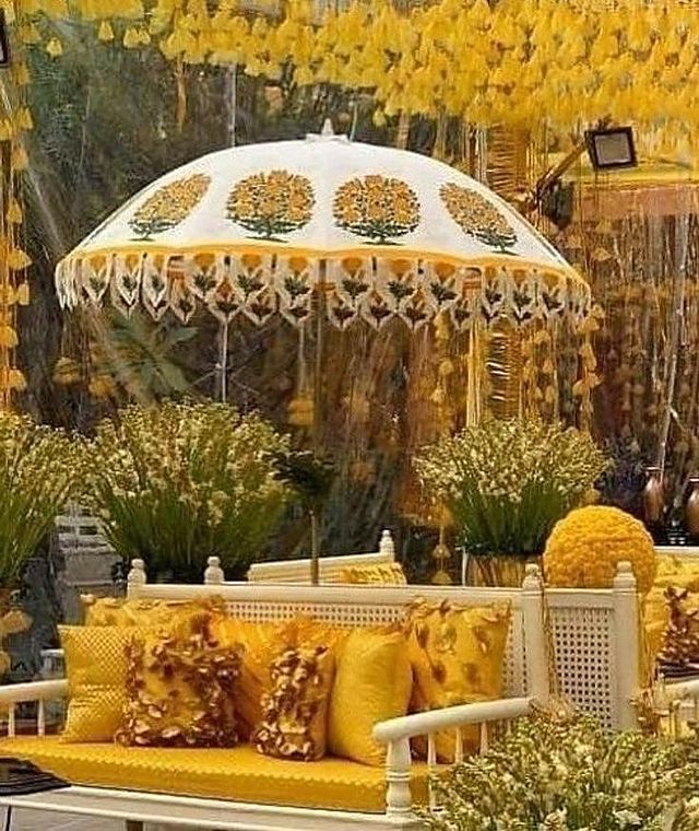 Haldi ceremony setup with marigold garlands and a hand painted parasol over a swing seat